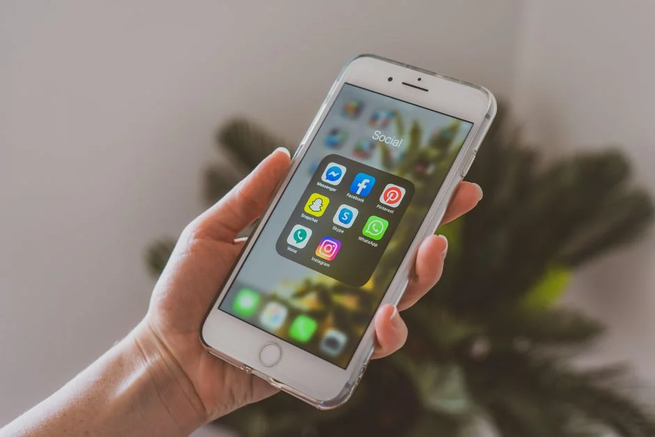 Vue plongeante d'une personne sans visage consultant un téléphone mobile pendant qu'elle travaille à la maison sur une table en marbre blanc avec des gadgets, un stylo et un crayon